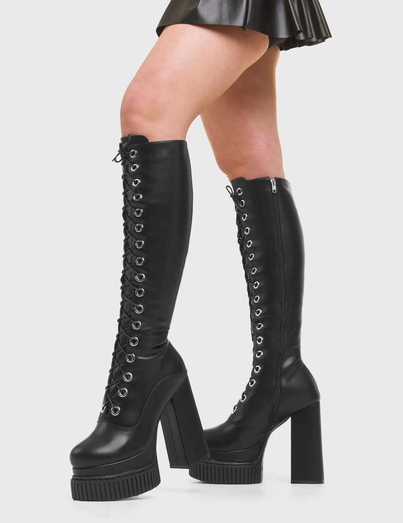 HIGH IN THE SKY Elevators Creeper Platform Knee High Boots in Black faux leather. These vegan western Boots feature a lace up design and Black stitch detailing. Made with eco-friendly materials and 100% cruelty-free, these boots are as ethical as they are trendy! - Heel Height - Knee high length - Black stitching - Black zip - Rubber grip sole - Rounded toe - 100% vegan SKU: LMF 3967 - BlackPU