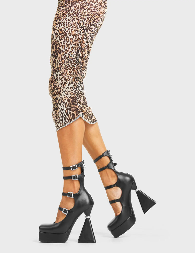 WONDERING Sympathy Platform Heels in black faux leather. These platform heels feature a flared heel that includes silver studded ring detailing on the heel, keeping it nice and classy. These heels also feature four adjustable straps with silver studded buckles and silver eyelets. Made with 100% vegan materials. - Platform Height - Flared Heel - Studded Detail - Silver Eyelets - Silver Ring - Four Adjustable Strap - Silver Studded Buckles - 100% Vegan SKU: LMF 4879 - BlackPU
